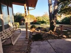 A porch with a bench and a tree in the background.
