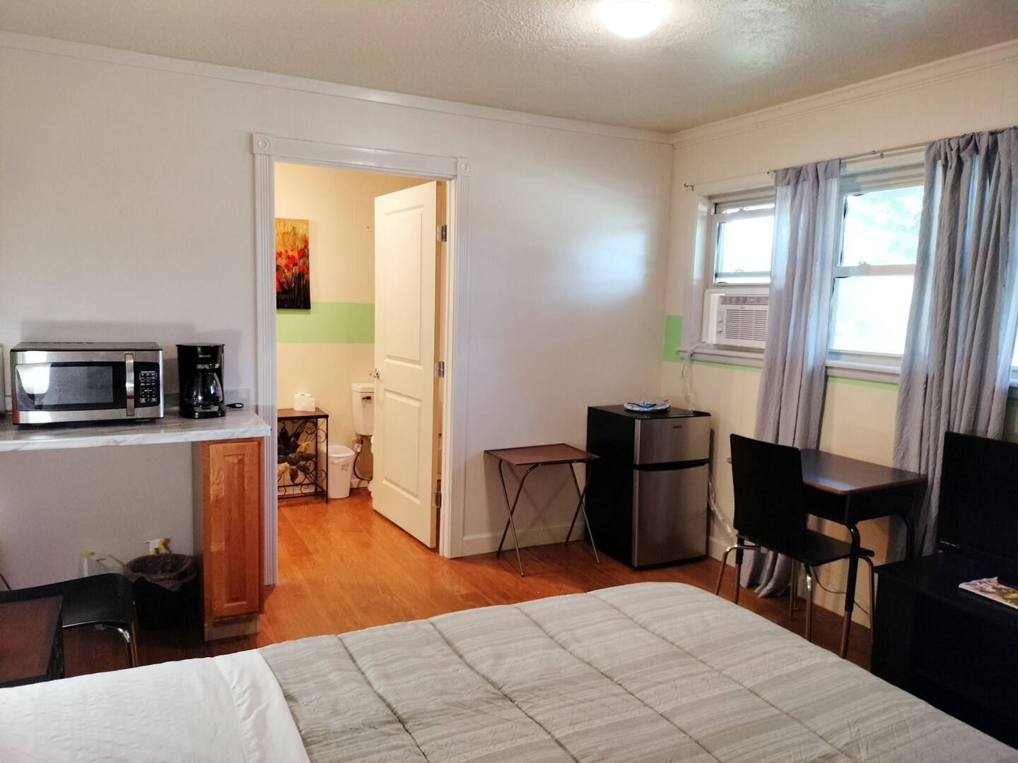 A bedroom with a bed a microwave and a refrigerator