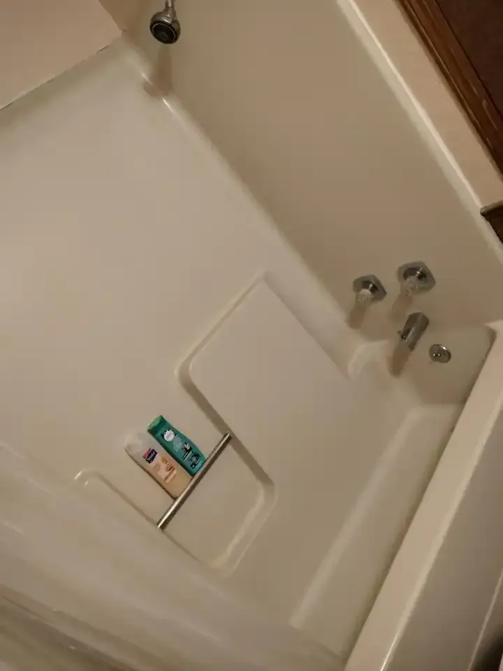 A white bathtub with a shower head and soap on the shelf