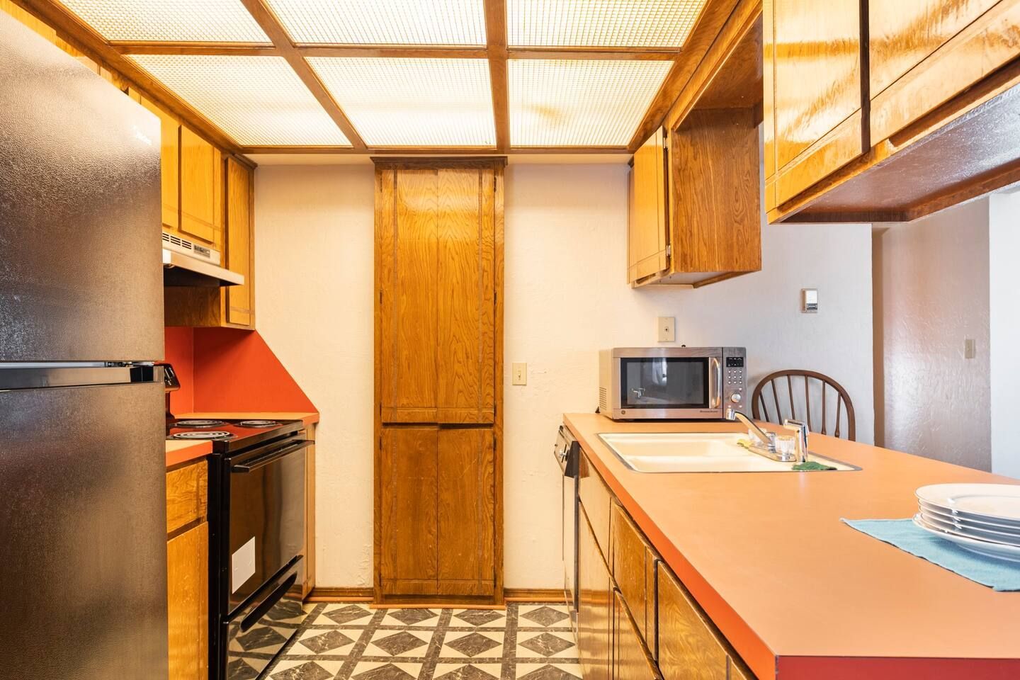 A kitchen with a refrigerator , stove , sink and microwave.