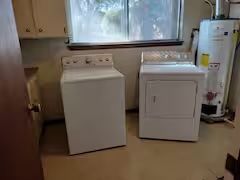 A washer and dryer are in a laundry room next to a window.
