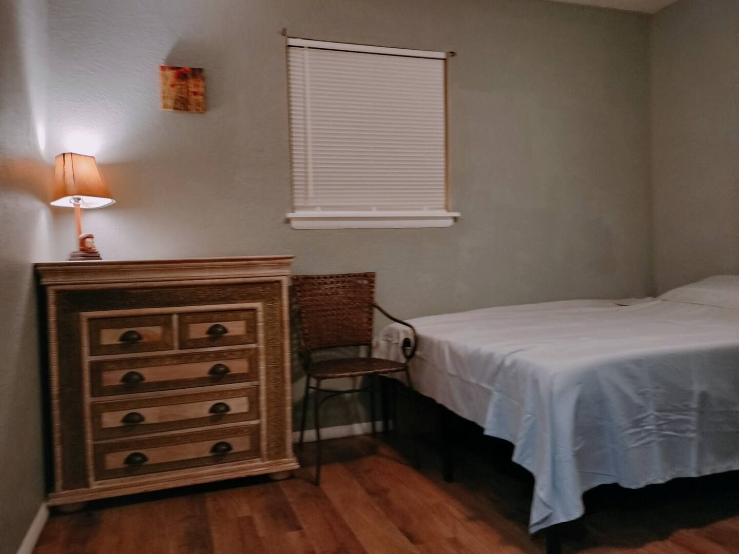 A bedroom with a bed a dresser and a chair