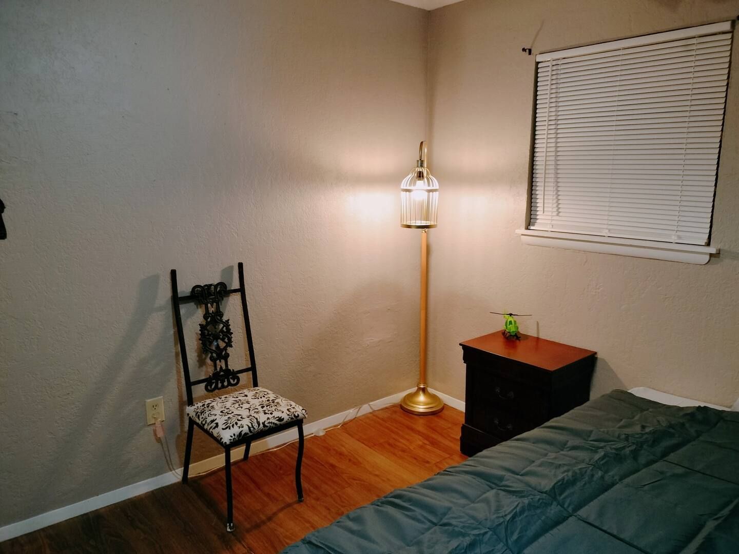 A bedroom with a bed a lamp and a chair