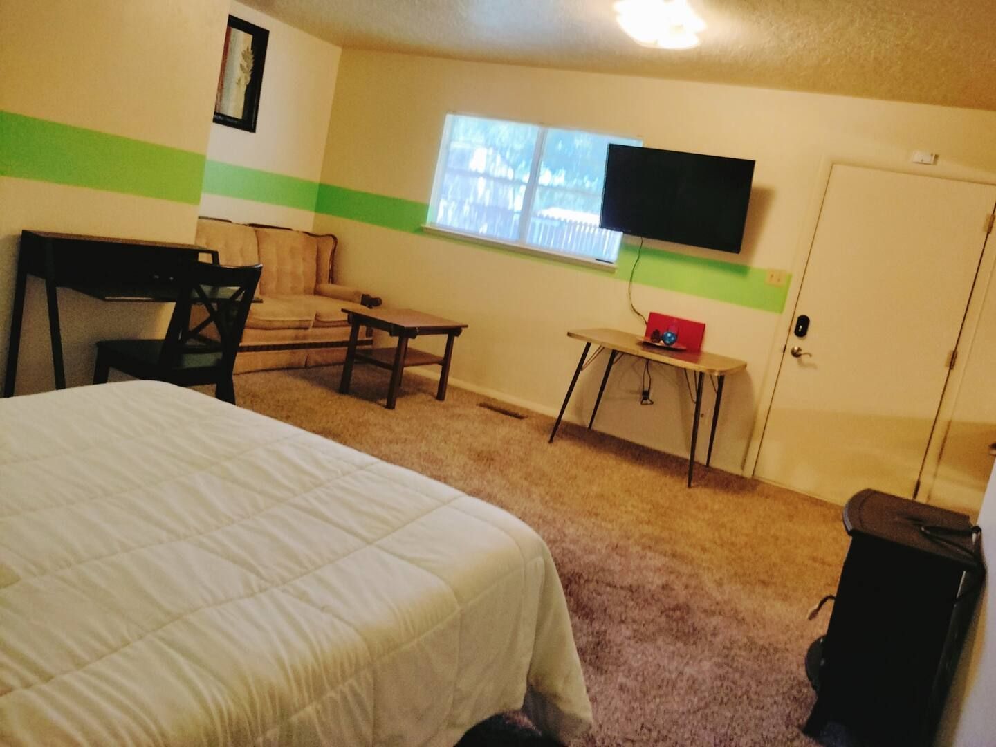 A bedroom with a bed a desk and a television