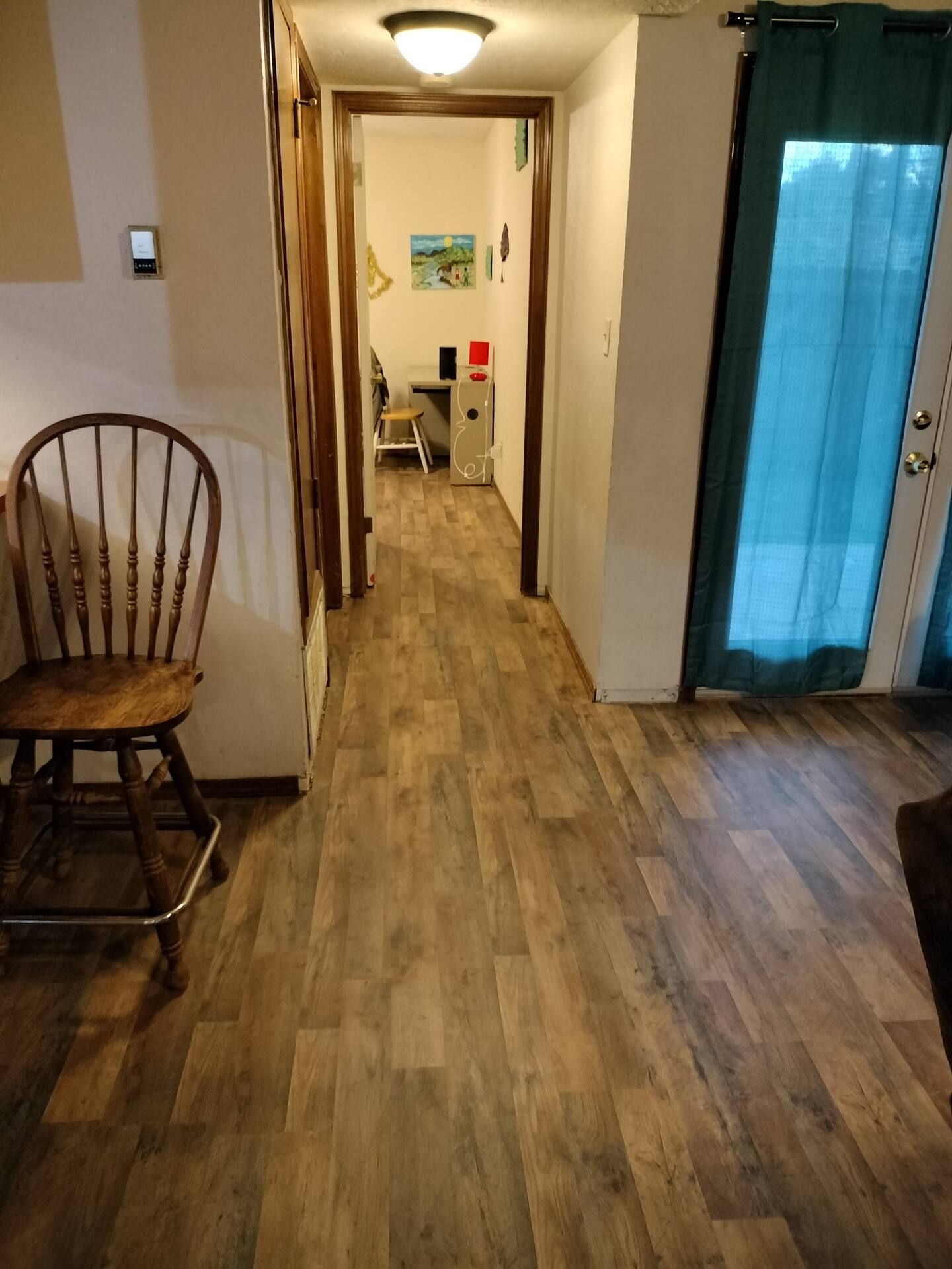 A hallway with hardwood floors and a wooden chair.