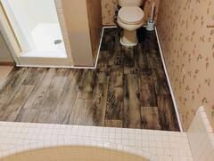 A bathroom with a toilet , shower and tiled floor.