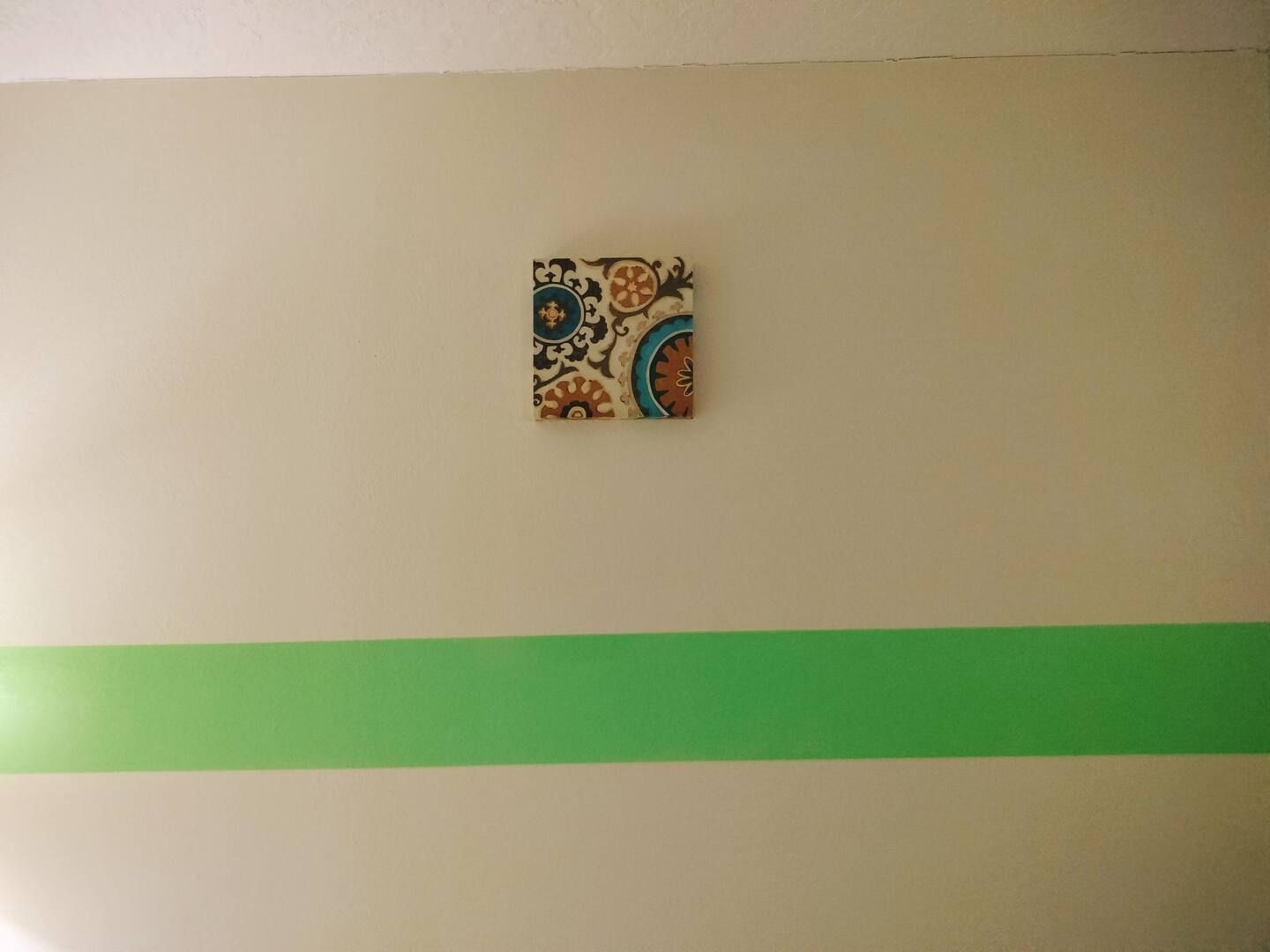 A picture is hanging on a wall next to a green stripe