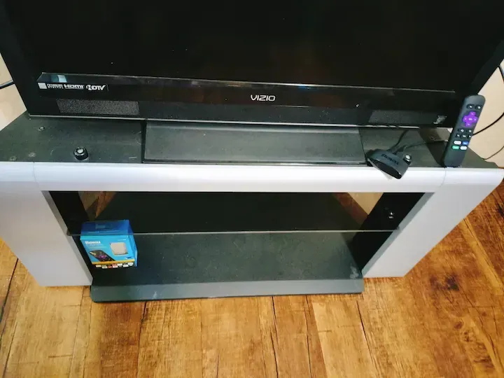 A vizio tv is sitting on top of a glass tv stand