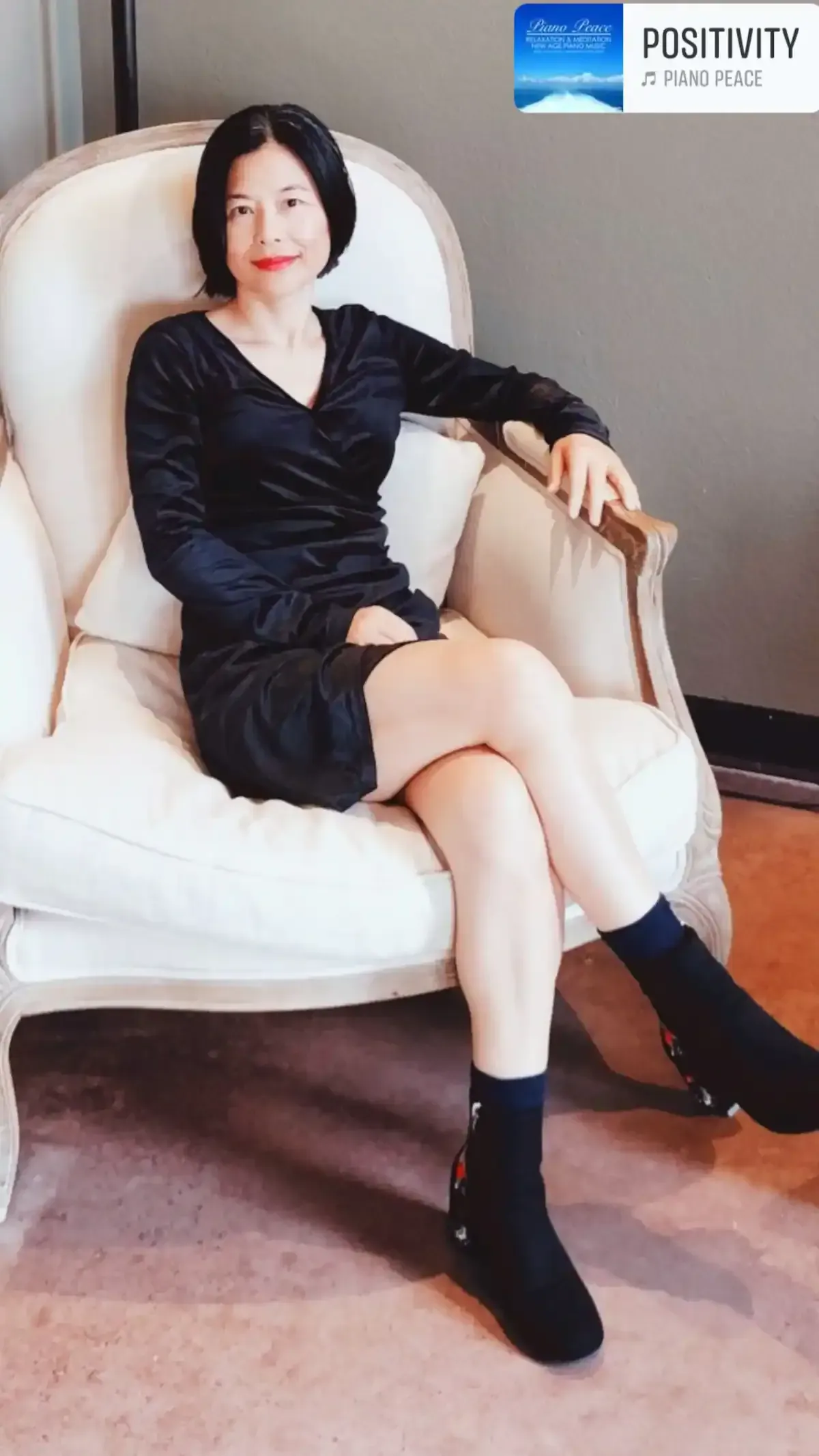 A woman in a black dress is sitting in a white chair