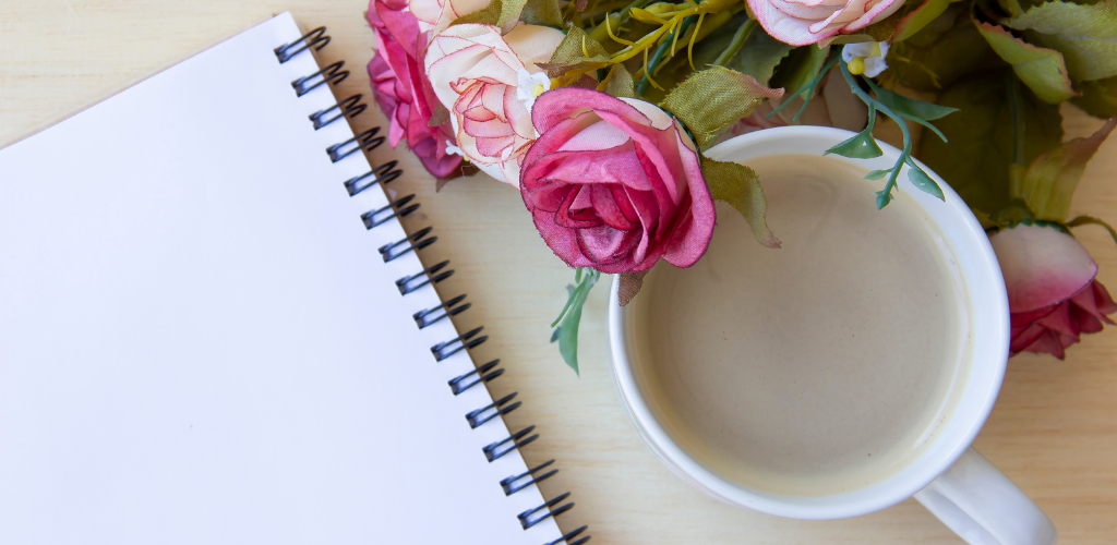 Blank notebook with roses and cup of water