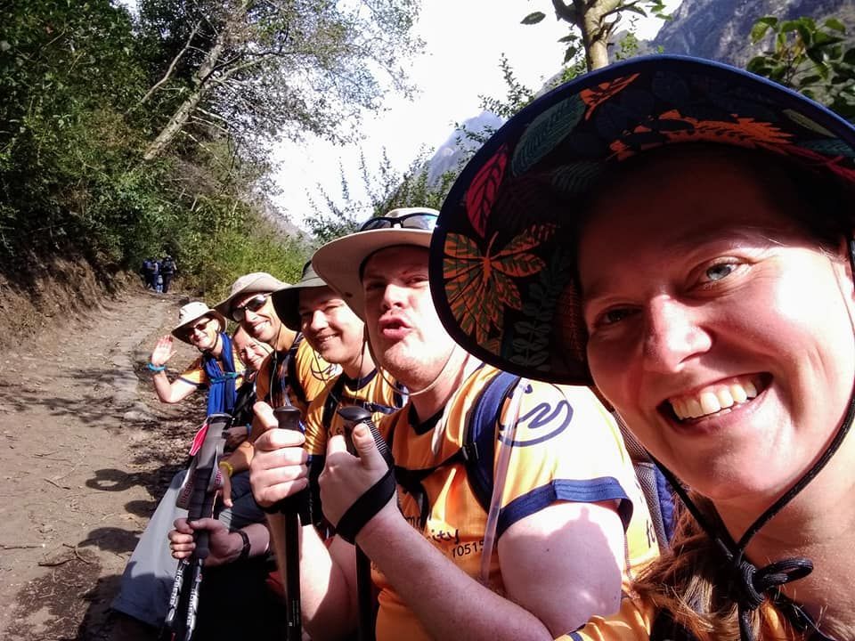Five people sitting down talking a selfie on a walking trail