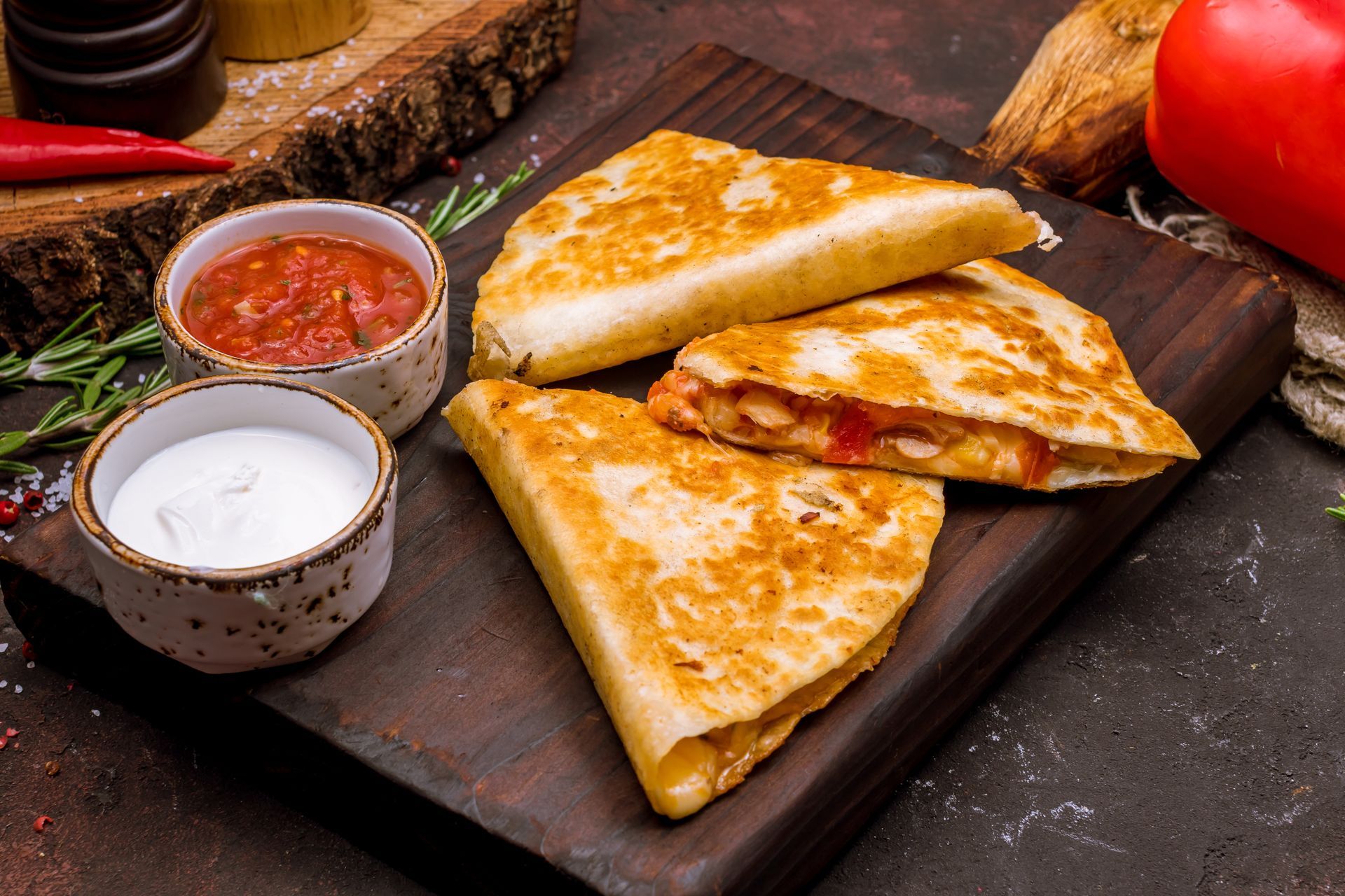 Quesadillas on a wooden board with dipping sauces; salsa and sour cream. Quesadillas on a wooden board with dipping sauces; salsa and sour cream.