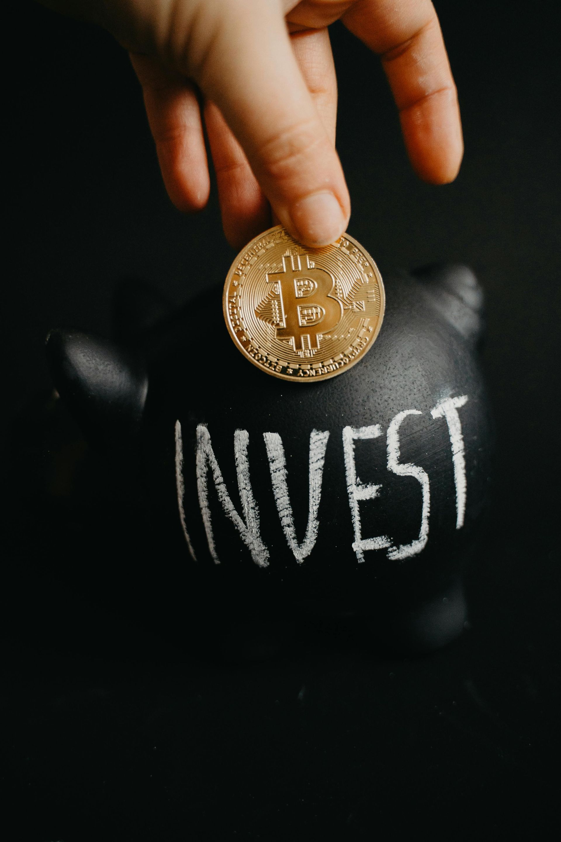 A person is putting a coin into a piggy bank that says invest.