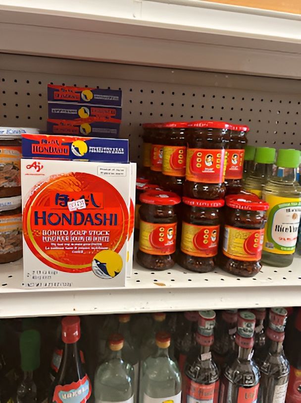 Shelf with various Asian food products, including Hondashi, jars of chili oil, and sauces.