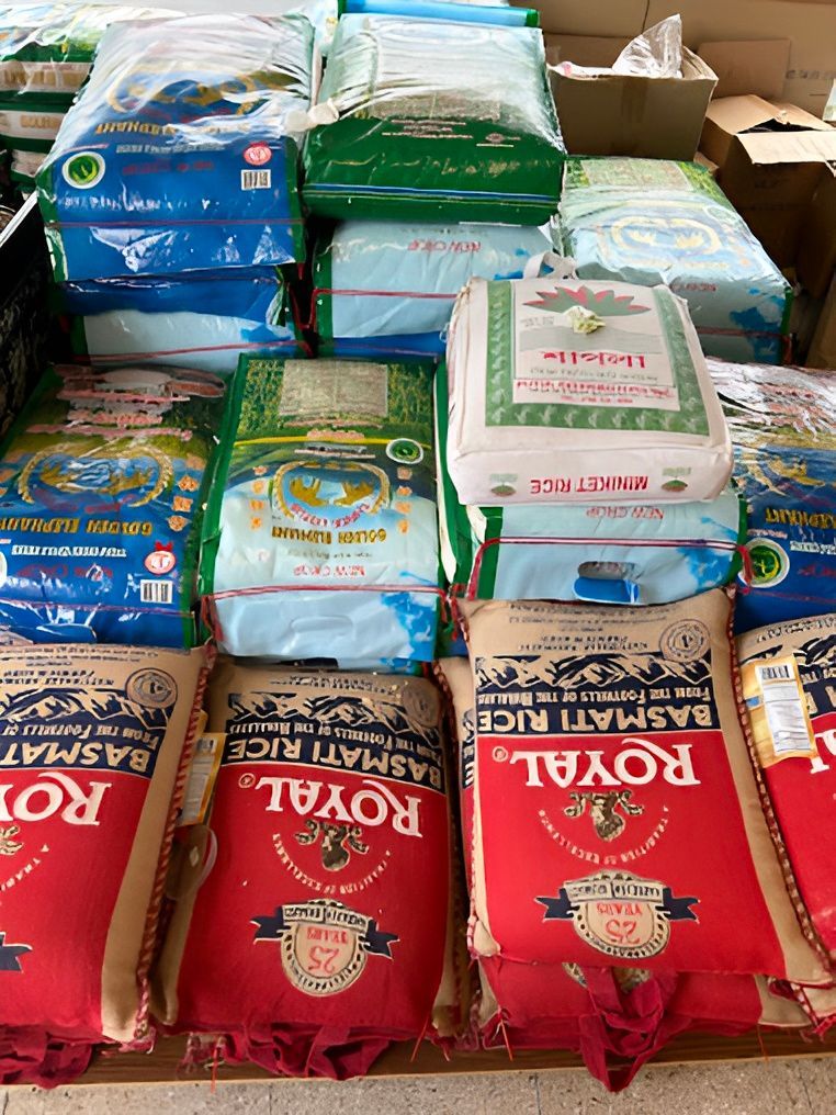 Bags of rice in various colors, including red, blue, green, and white, stacked on shelves.