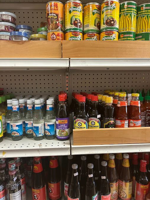 Shelves of Asian food products, including canned goods, sauces, and bottled ingredients in a market.