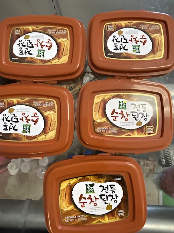 Five brown containers of Korean soybean paste, labeled with Korean text and a circular logo.