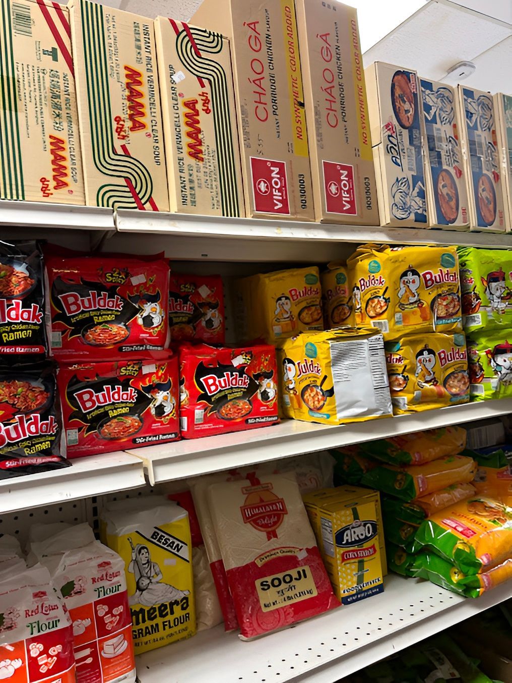 Shelves of Asian food products in a store, including noodles and rice.