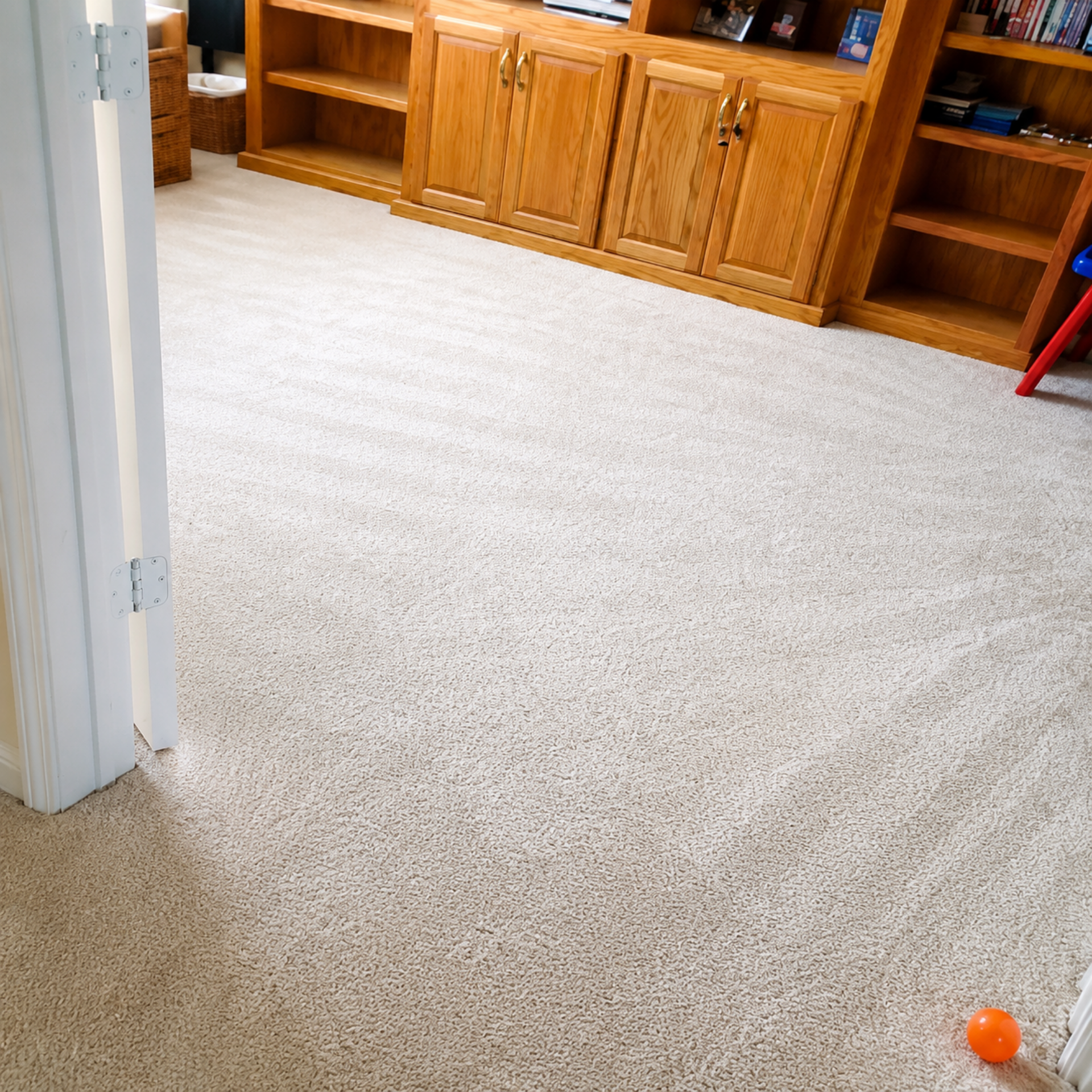 Carpeted room with wooden cabinets and a small orange ball on the floor near the bottom right.
