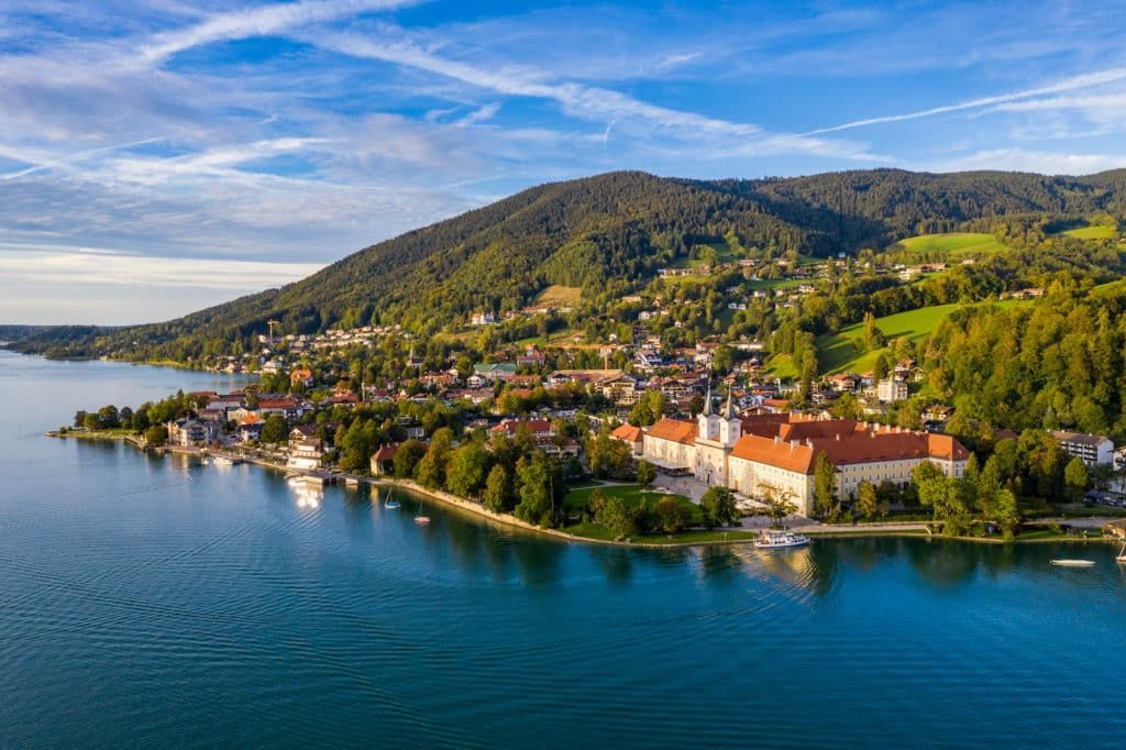An aerial view of a small town on the shore of a lake surrounded by mountains.