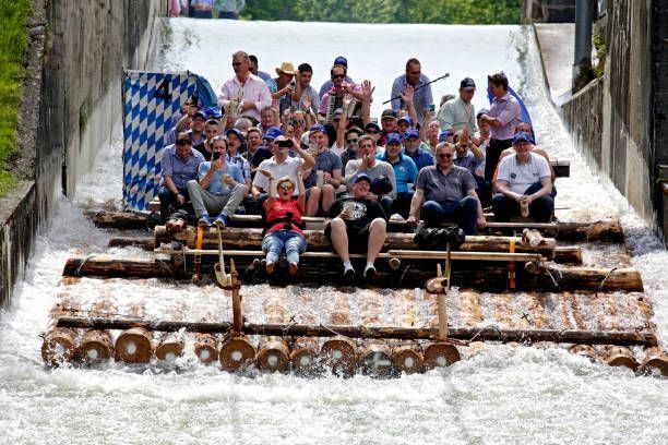 A group of people are sitting on a dock next to a body of water.
