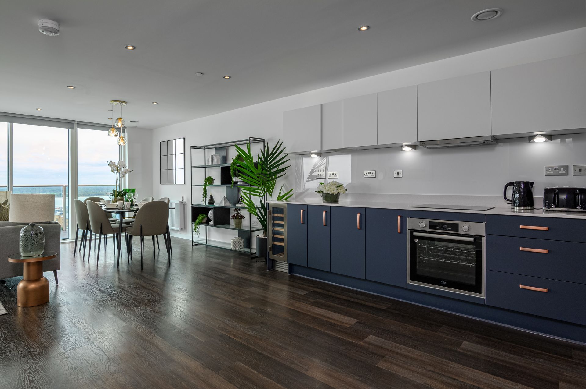 A kitchen with blue cabinets and stainless steel appliances in a living room.