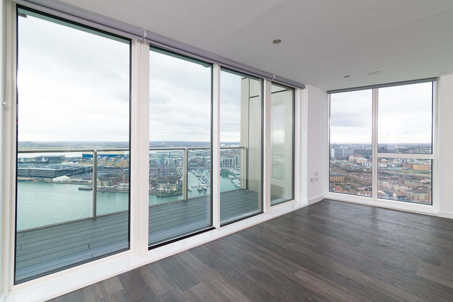 An empty room with a balcony and lots of windows