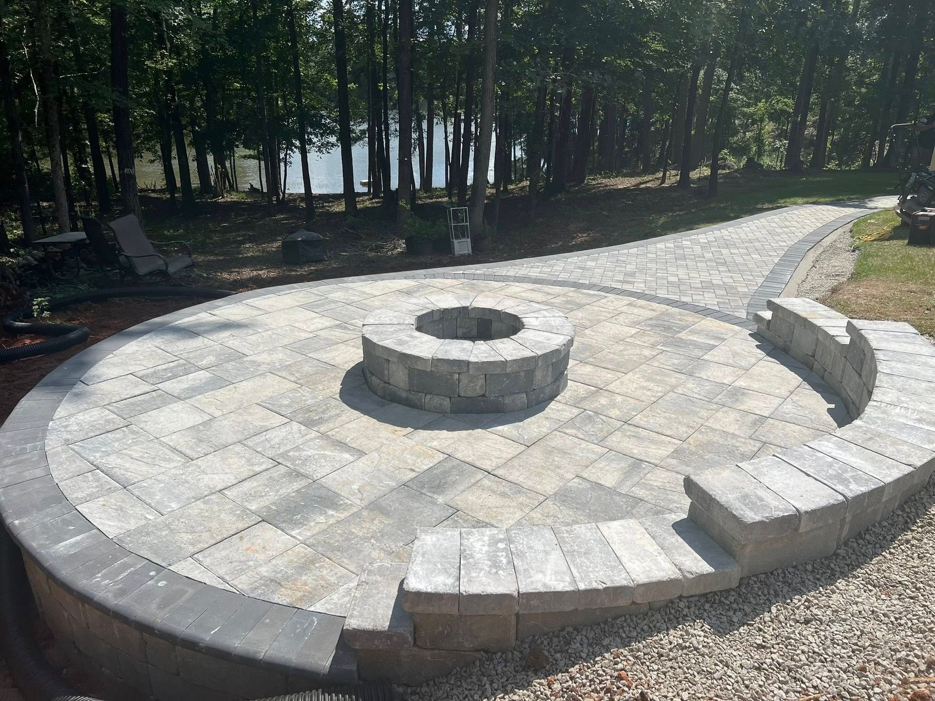 Circular stone fire pit with curved benches in a wooded outdoor area