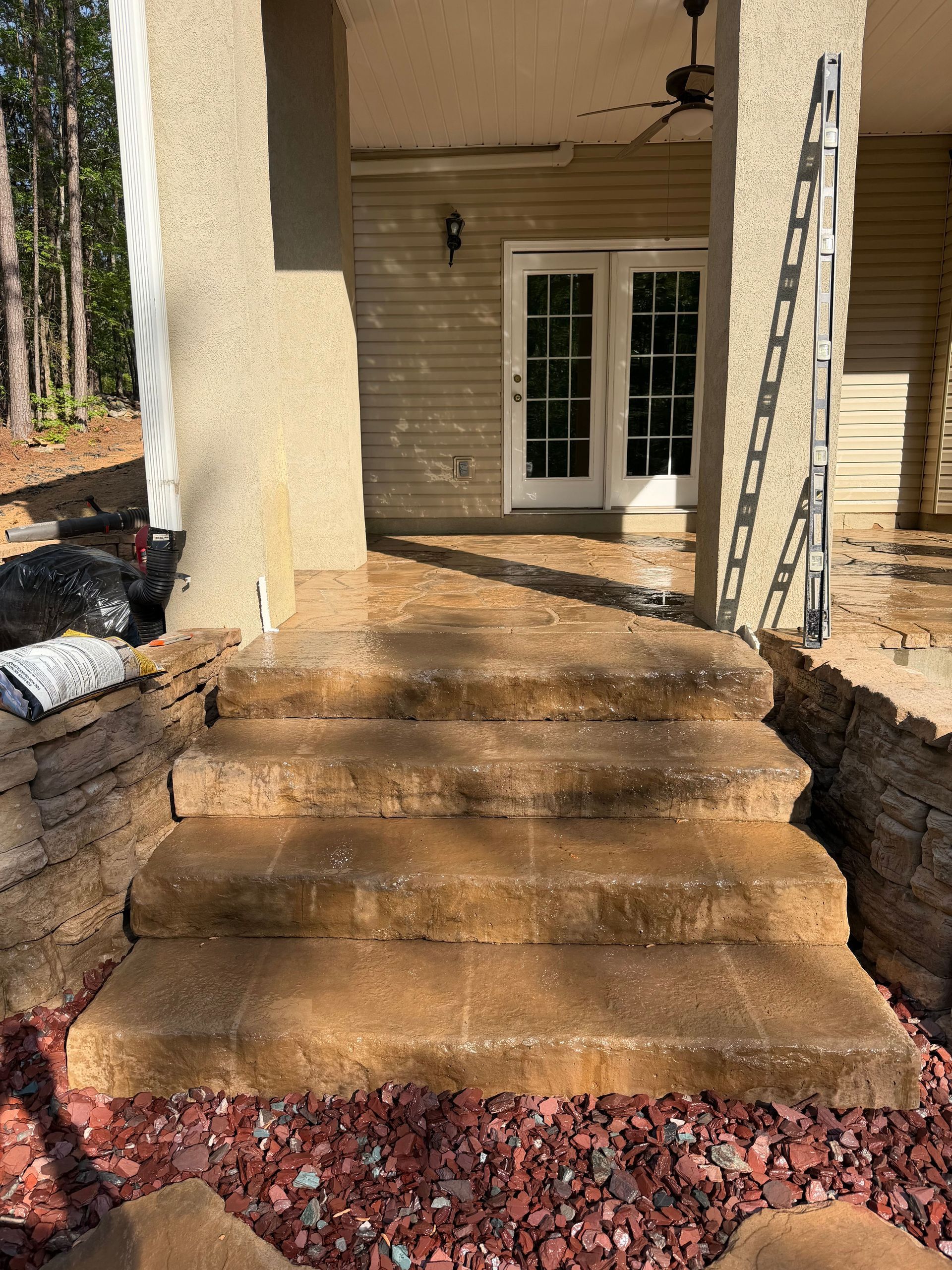 Front entrance with concrete steps, tan stucco walls, white door, and a ladder on the right.