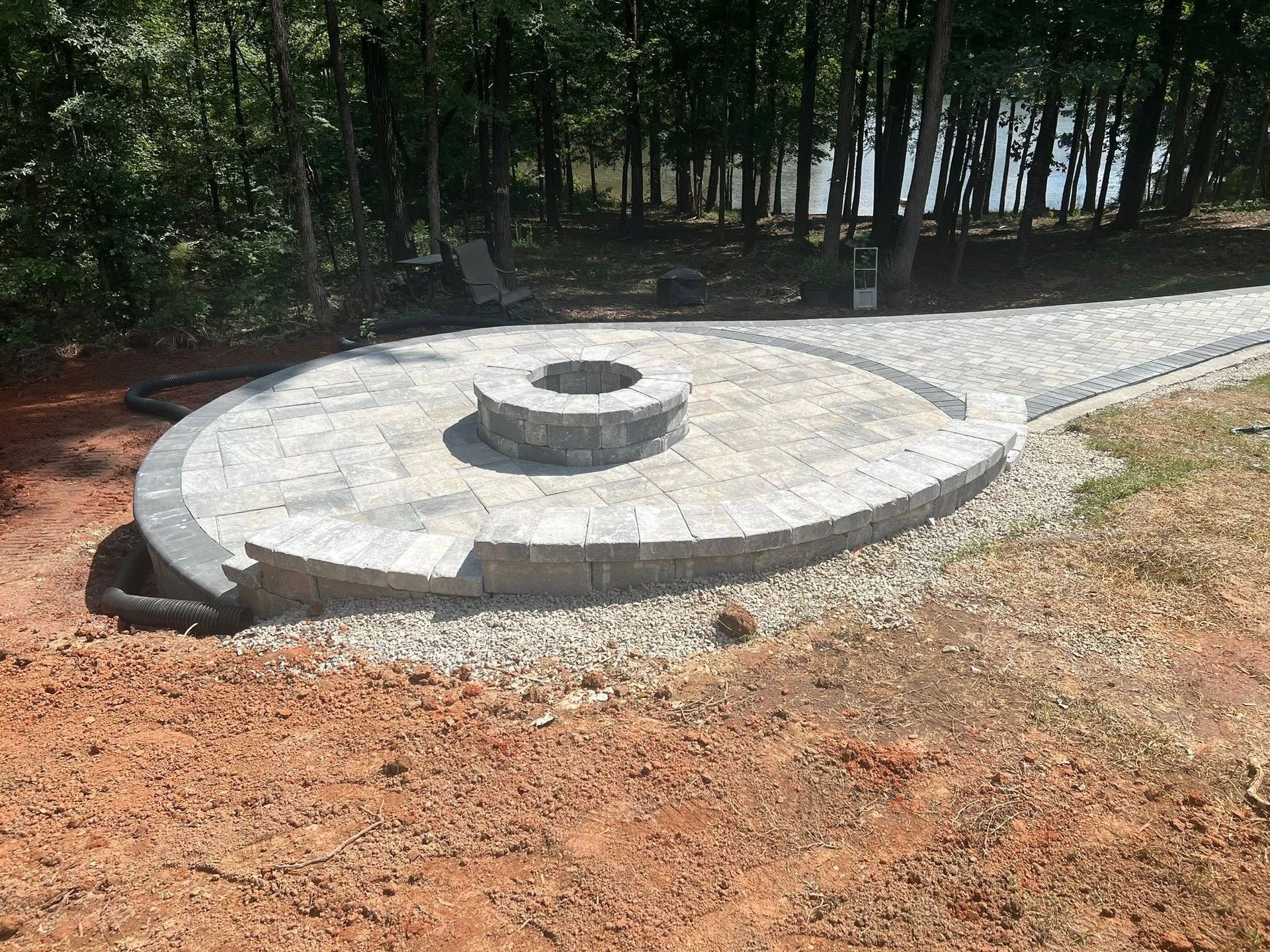 Circular concrete structure in a wooded area with a raised center and gravel path beside it