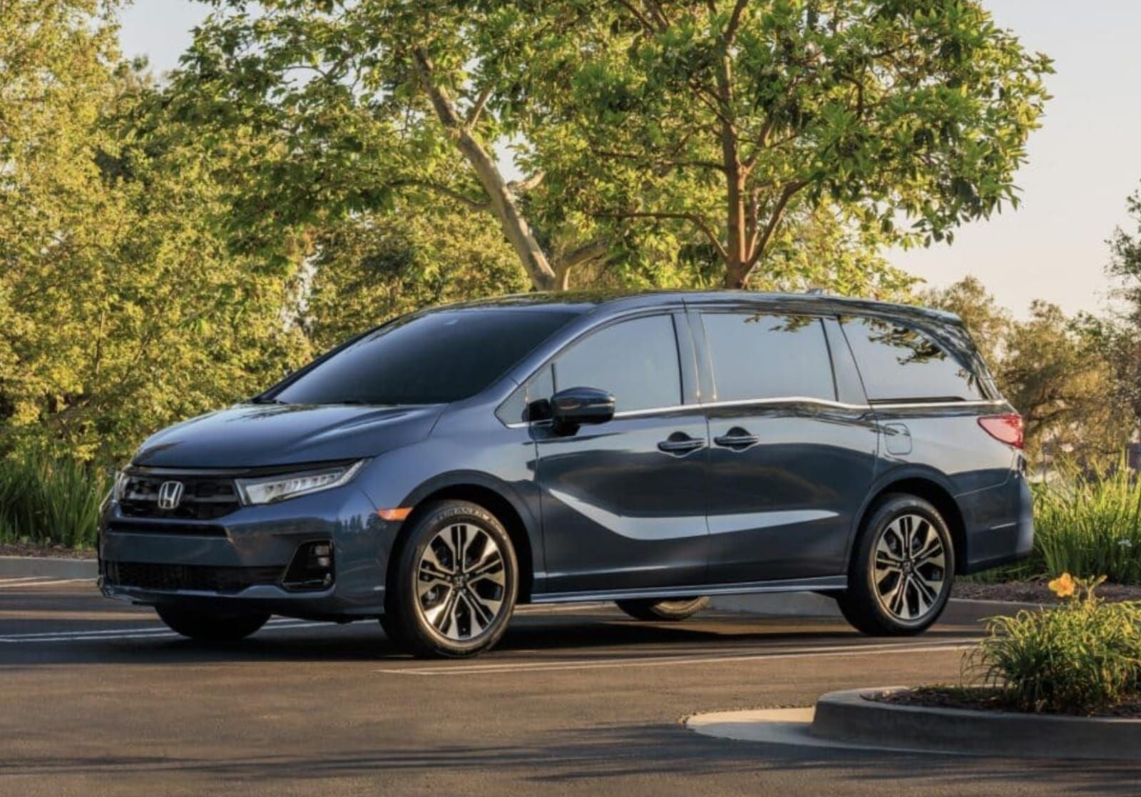 A gray honda minivan is parked in a parking lot.