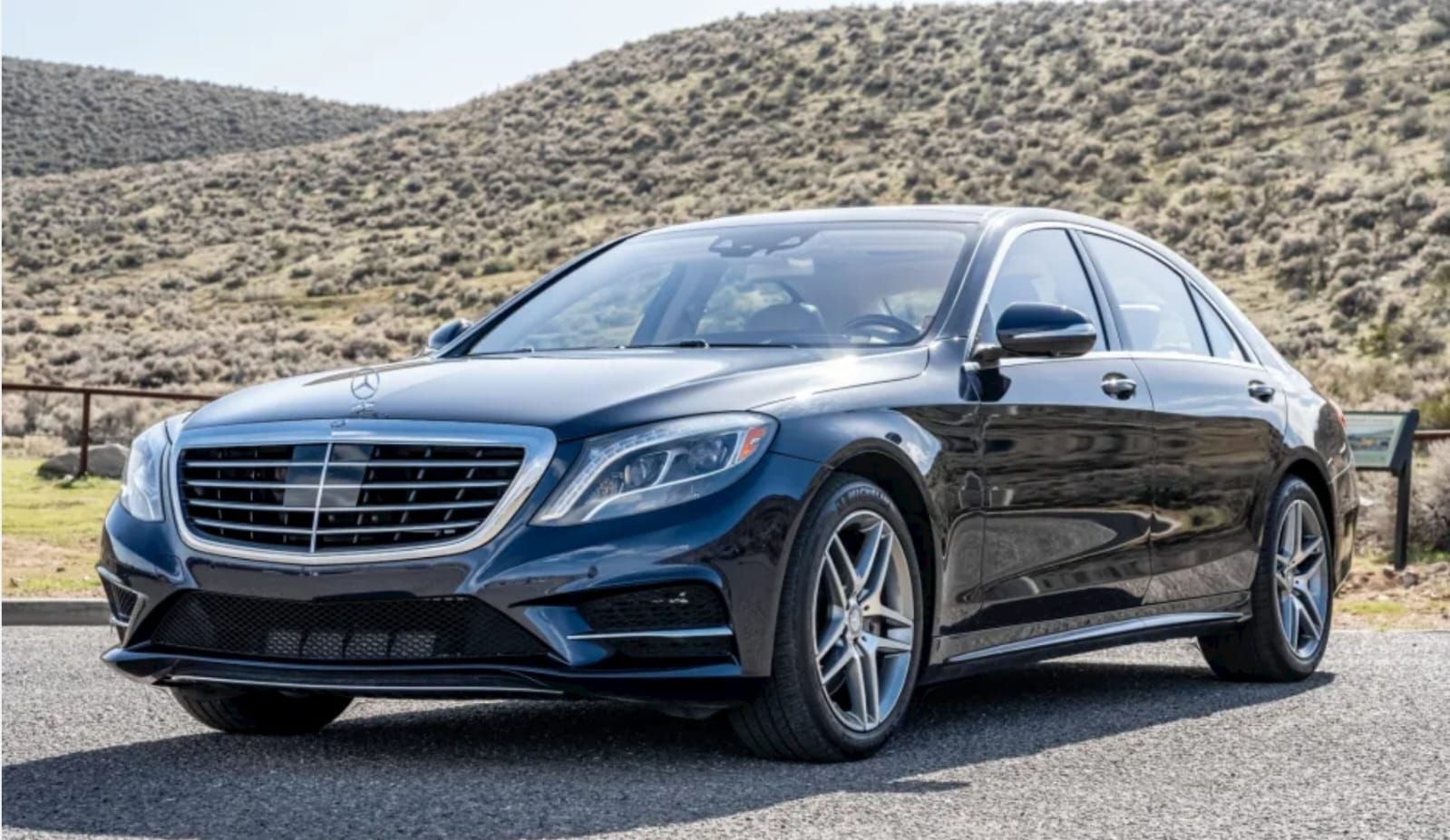 A black mercedes benz s class is parked on the side of the road.