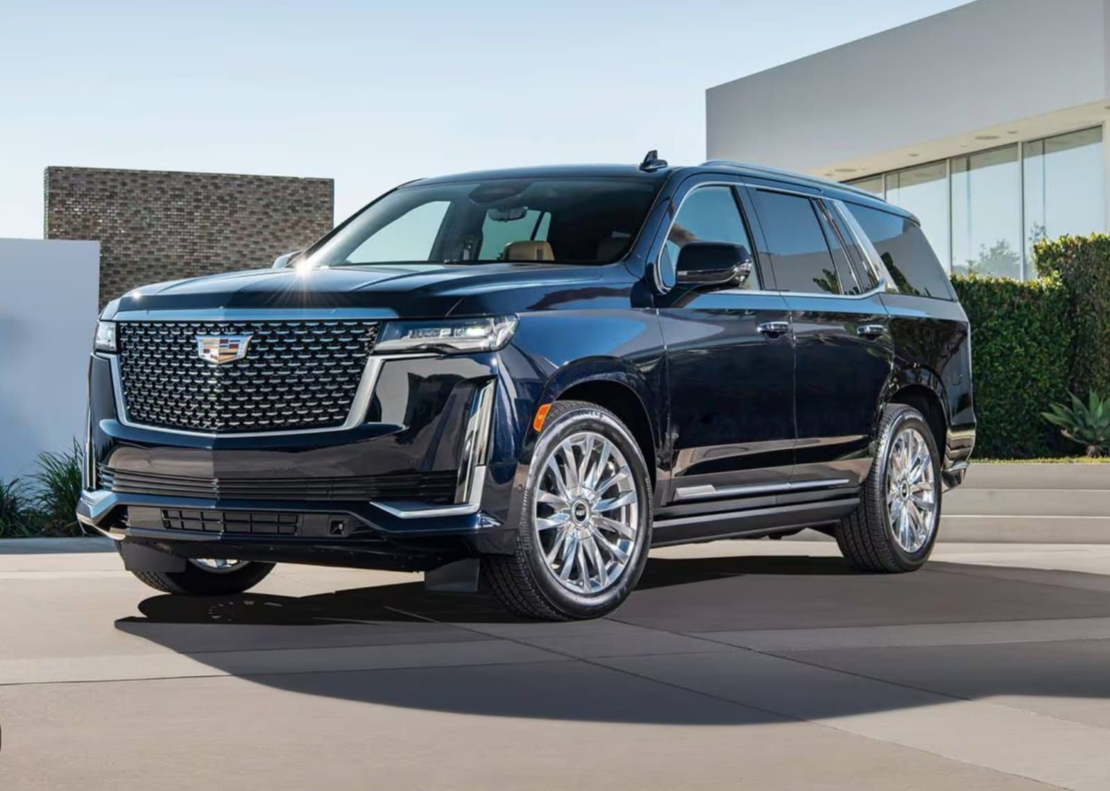 A black cadillac escalade is parked in front of a building.