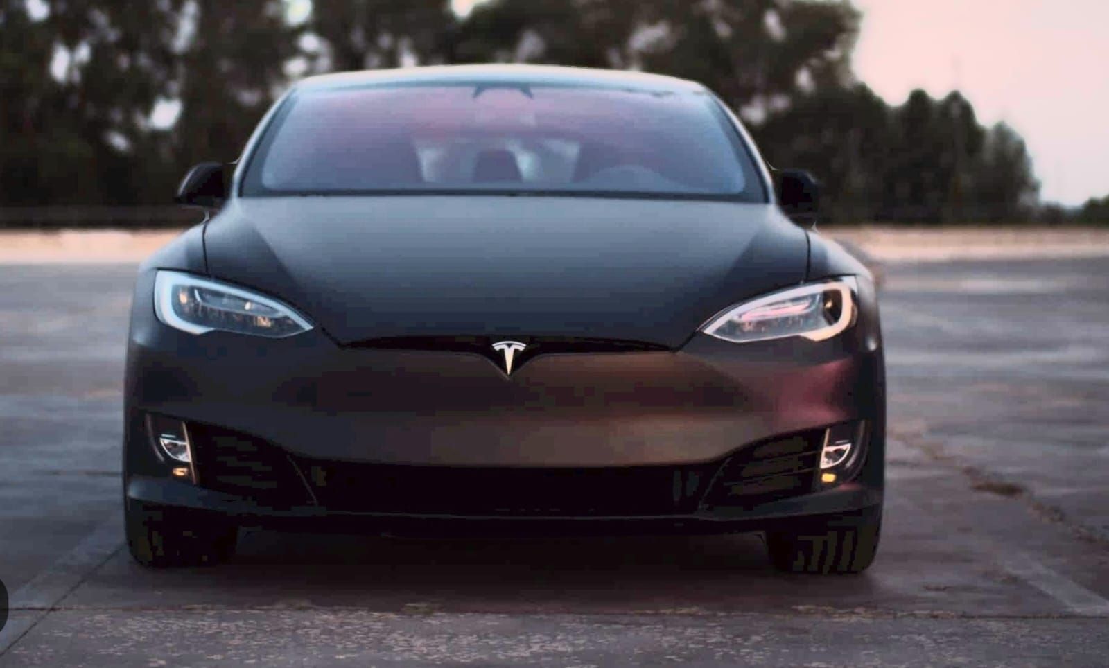 A black tesla model s is parked in a parking lot.