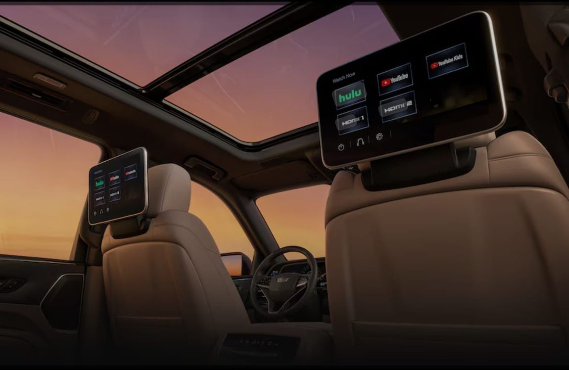 The interior of a car with a sunroof and two headrest monitors.