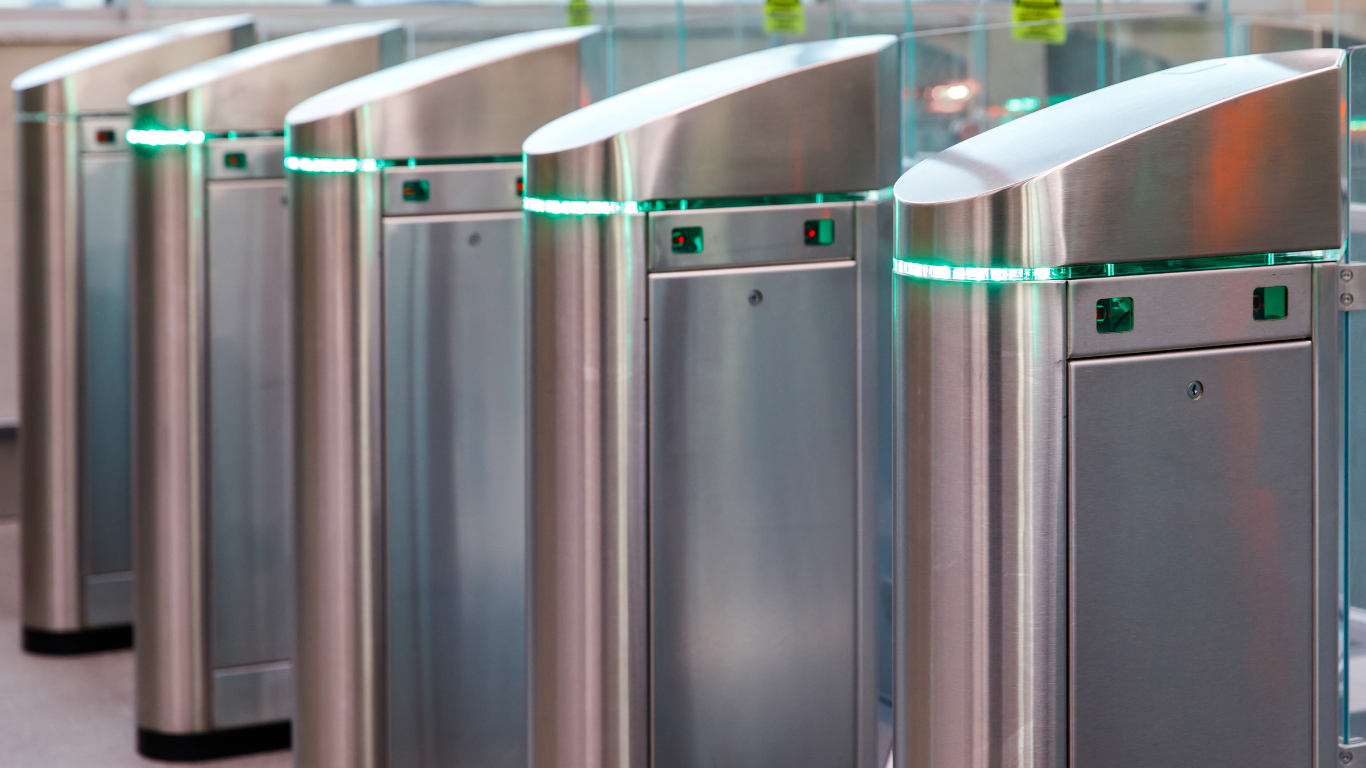 A row of stainless steel security turnstiles are lined up in a row.