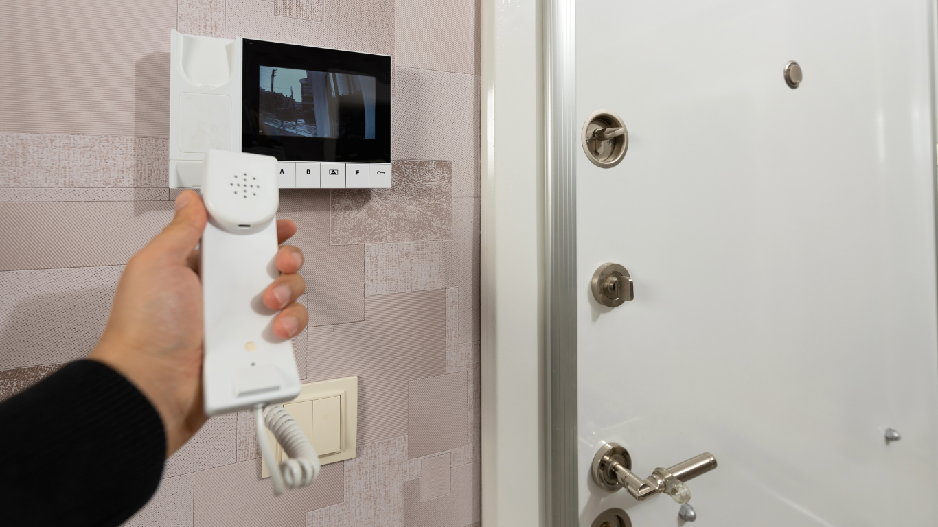 A person is holding an intercom system in front of a door.
