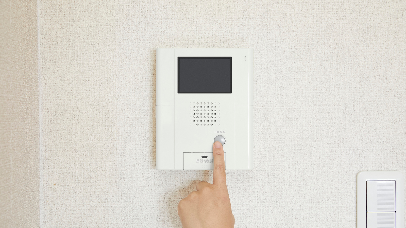A person is pressing a button on a doorbell on a wall.