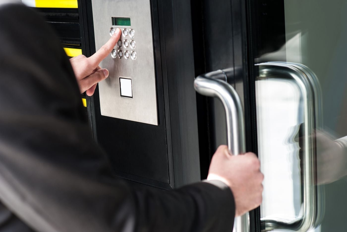 A man is using an access control keypad to open a door.