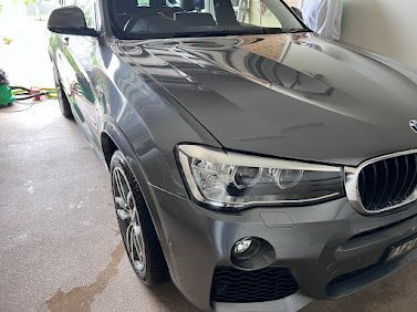 Grey BMW SUV parked in a garage, front-left view.
