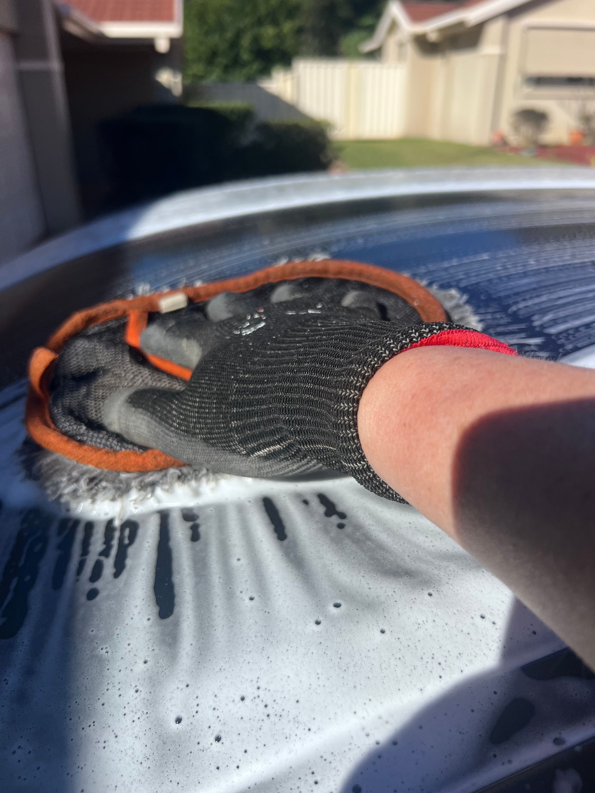 Gloved Hand Scrubbing A Car Windshield With SOAP Suds Outdoors — Car Detailing Mobile Cleaning Co In Lake Cathie, NSW