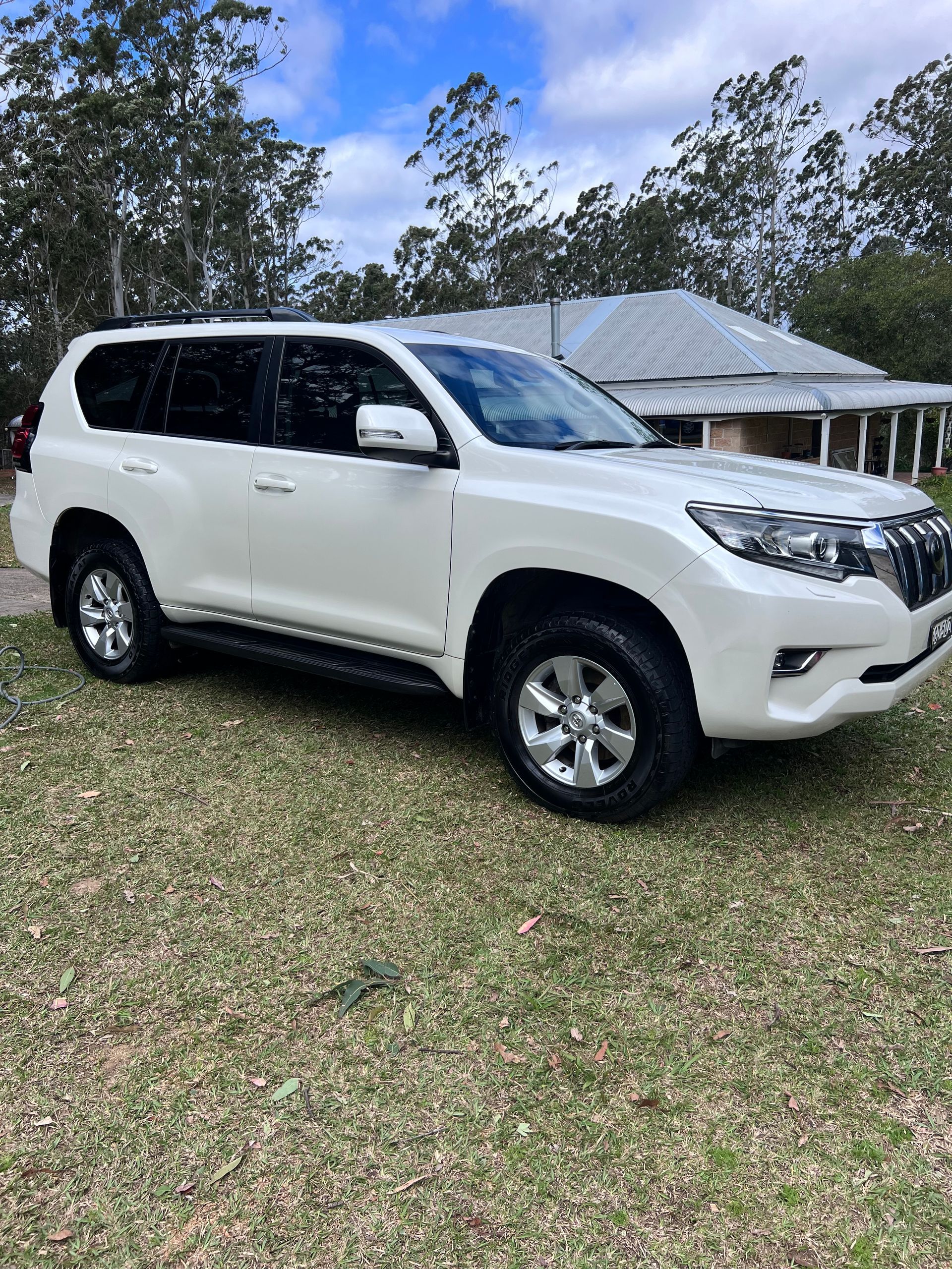 White SUV Parked On Grass In Front Of A House With Trees In The Background — Car Detailing Mobile Cleaning Co In Port Macquarie, NSW