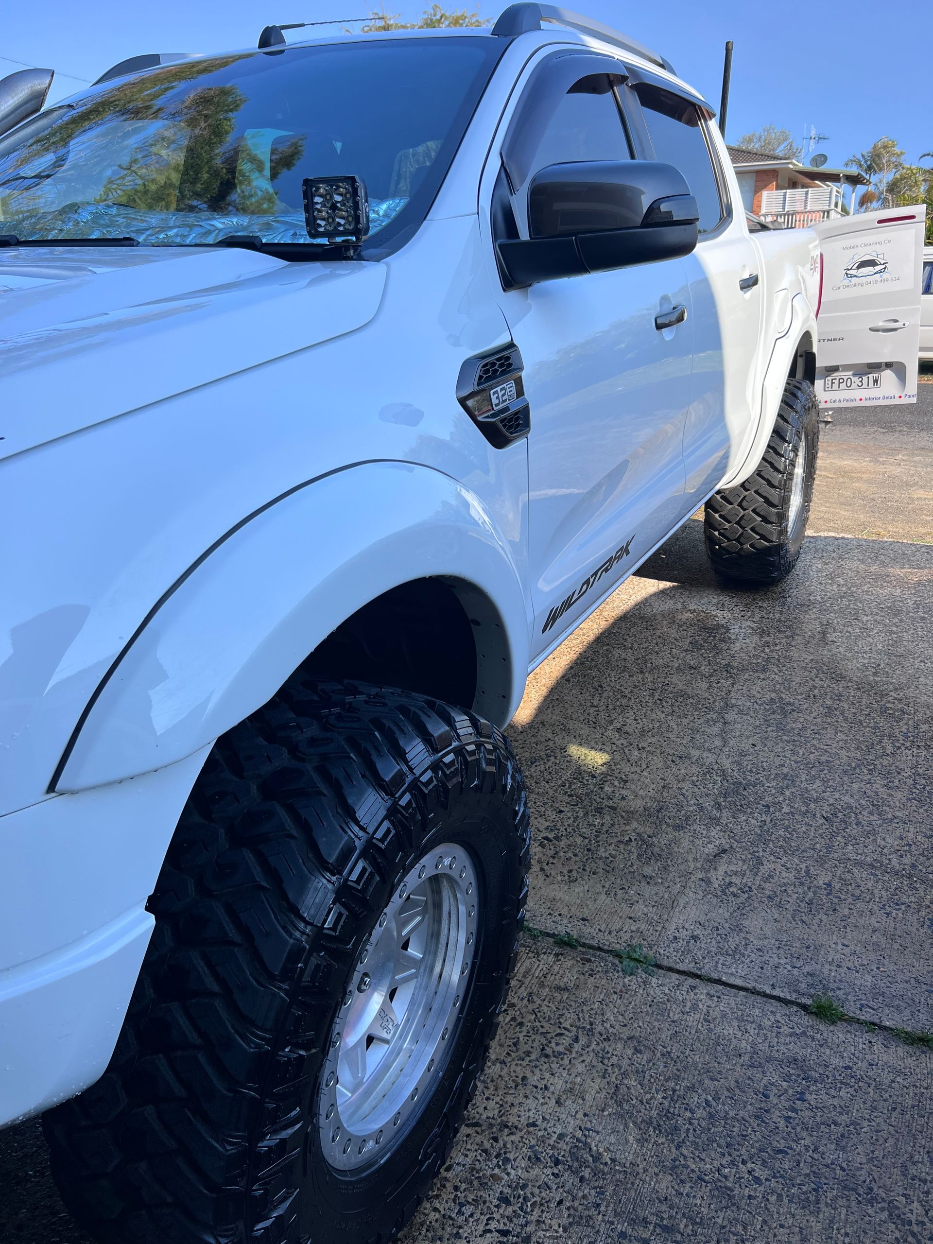 White Lifted Pickup Truck With Large Off-road Tires Parked Outdoors In Sunlight — Car Detailing Mobile Cleaning Co In Wauchope, NSW
