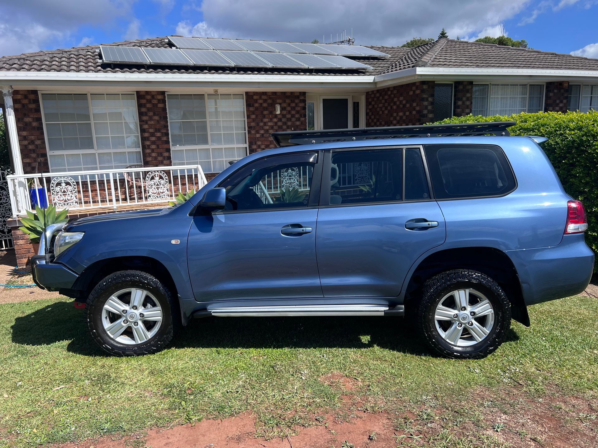 Blue SUV Parked On A Grassy Lawn In Front Of A Brick House With A White Porch — Car Detailing Mobile Cleaning Co In Port Macquarie, NSW