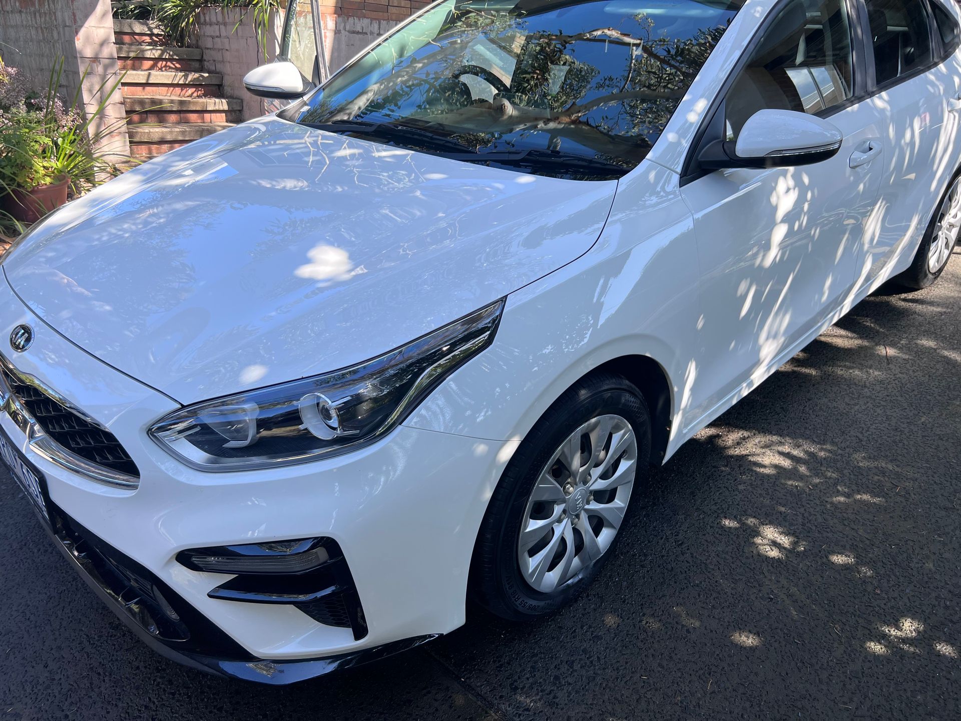 White Compact Car Parked on a Driveway in Dappled Sunlight — Car Detailing Mobile Cleaning Co In Port Macquarie, NSW