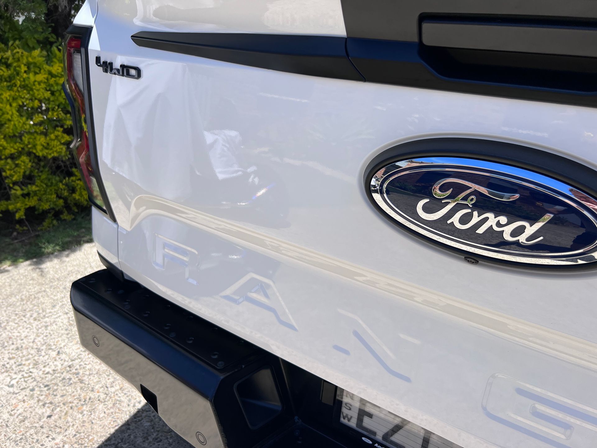 Close-up of a white Ford F-150 tailgate with the Ford emblem and rear bumper visible — Car Detailing Mobile Cleaning Co In Port Macquarie, NSW