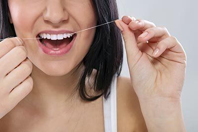 Woman Using Dental Floss — Orange, CT — New England Dental Health Services PC