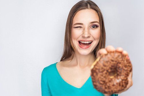Woman Holding a Donut — Orange, CT — New England Dental Health Services PC