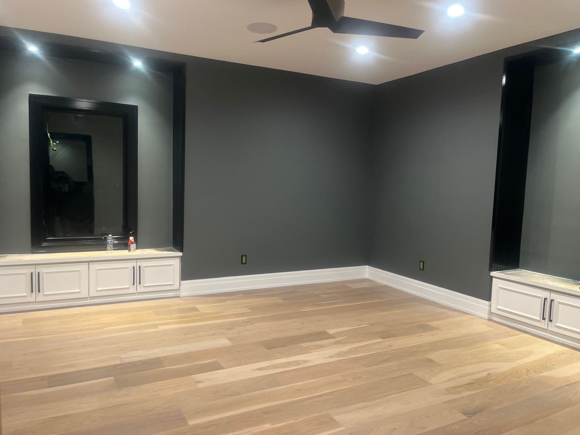 An empty room with a ceiling fan and a mirror on the wall.