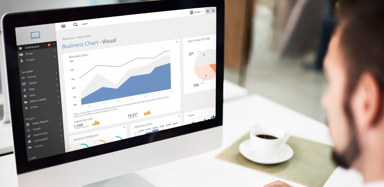 A man is sitting at a desk looking at a computer screen.